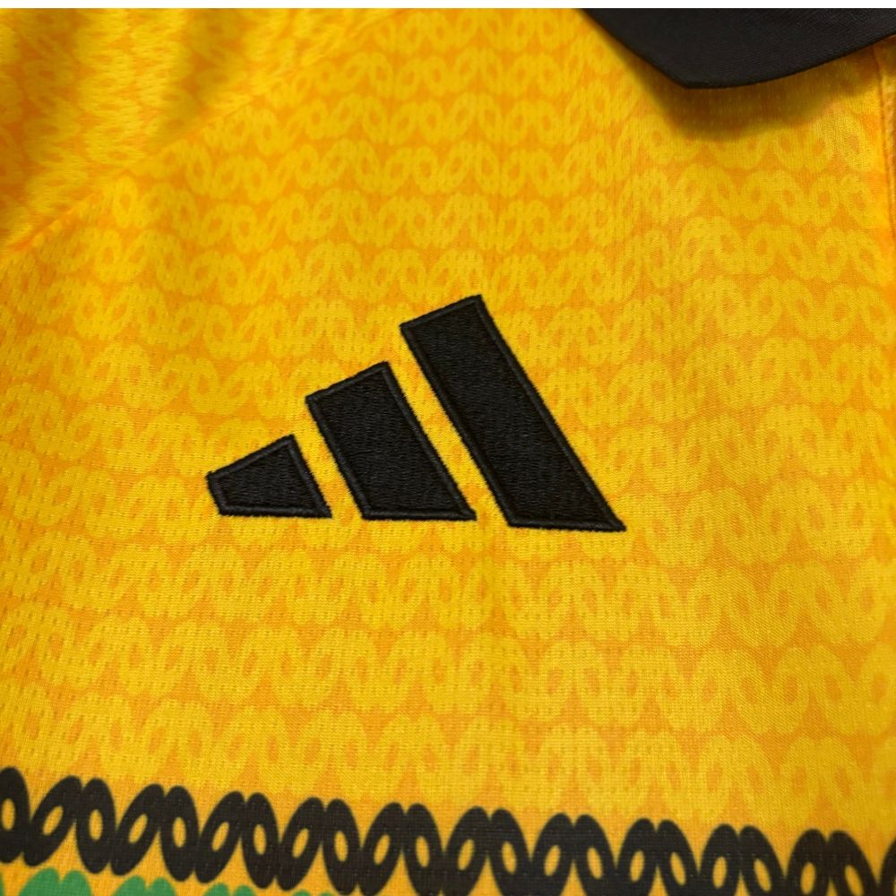 Camisa Adidas Jamaica 26/27 Home, , PIQUE DE JOGADOR, A Camisa Adidas Jamaica 26/27 Home representa o uniforme principal da seleção jamaicana para o ciclo da Copa do Mundo de 2026, trazendo um dos designs mais criativos e culturais do futebol atual. Inspirada diretamente na cultura reggae e no legado de Bob Marley, a camisa apresenta uma base em amarelo vibrante com padrões horizontais em verde, vermelho e dourado. Esses elementos fazem referência às cores tradicionais da Jamaica e ao estilo icônico do arti