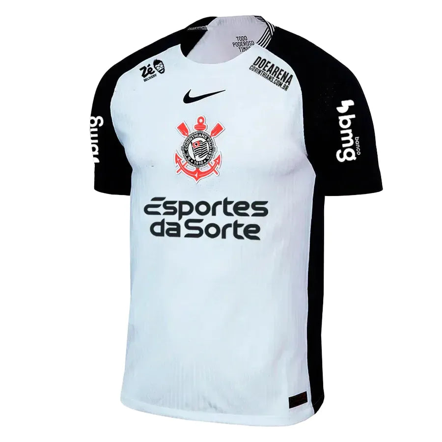 Camisa Nike Corinthians I 25/26 Jogador C/ Patrocínios, Camisa Futebol, Adidas, O DIA QUE A LOUCURA VIROU MUNDIAL Inspirada no mundial de 2000, a nova camisa I do Corinthians é inteiramente branca, com as áreas do ombro em preto, e o escudo do Corinthians e o swoosh centralizados no peito, em referência à icônica camisa campeã mundial. Dentro da gola, à altura do pescoço, um emblema com a inscrição "Todo Poderoso Timão" homenageia o grito que ganhou popularidade durante a competição e empurrou o Corinthians
