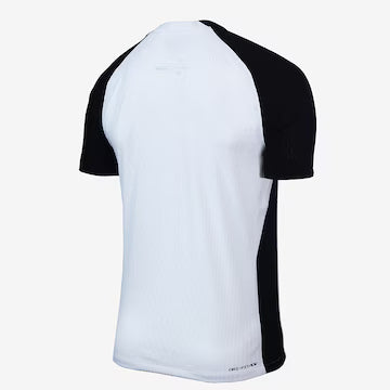 Camisa Nike Corinthians I 25/26 Jogador, Camisa Futebol, Nike, O DIA QUE A LOUCURA VIROU MUNDIAL Inspirada no mundial de 2000, a nova camisa I do Corinthians é inteiramente branca, com as áreas do ombro em preto, e o escudo do Corinthians e o swoosh centralizados no peito, em referência à icônica camisa campeã mundial. Dentro da gola, à altura do pescoço, um emblema com a inscrição "Todo Poderoso Timão" homenageia o grito que ganhou popularidade durante a competição e empurrou o Corinthians rumo ao título. 