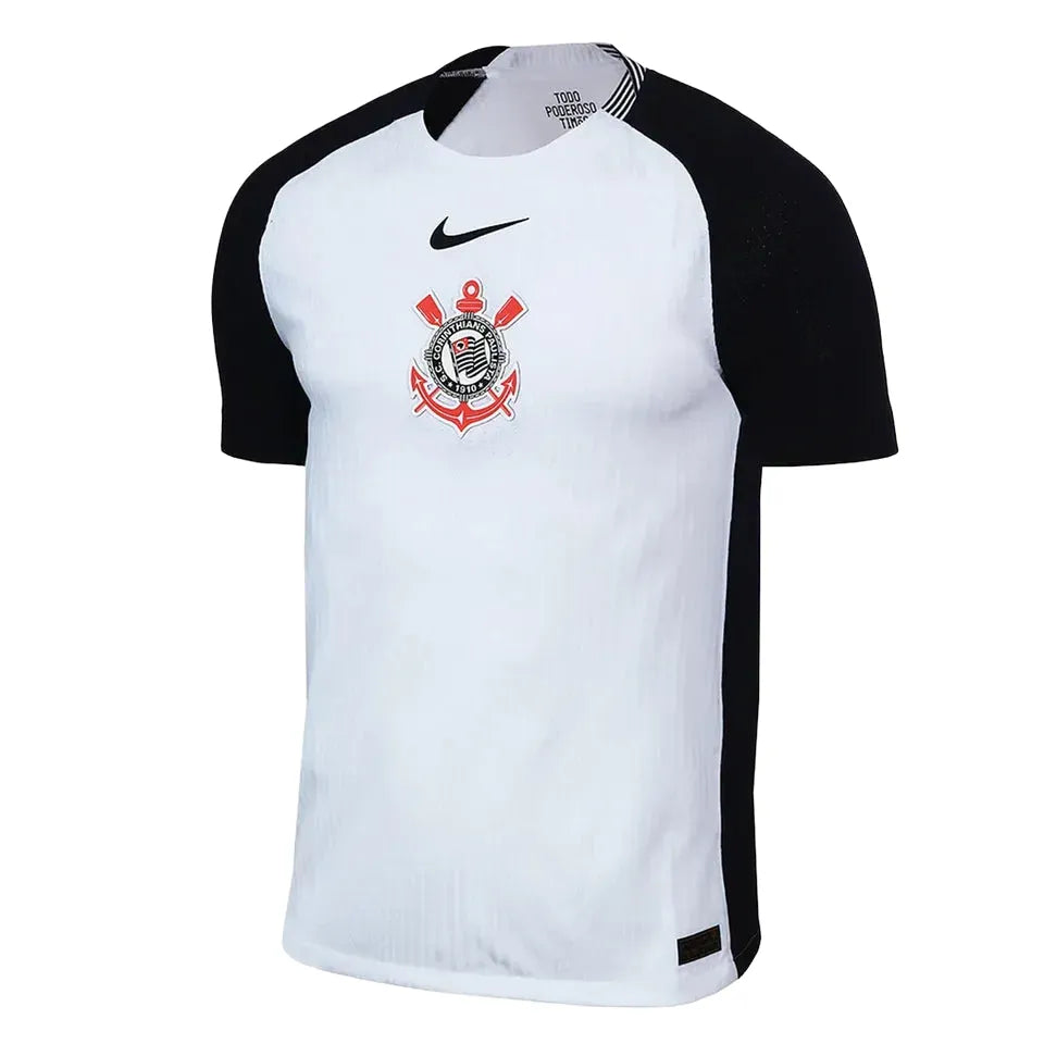 Camisa Nike Corinthians I 25/26 Jogador, Camisa Futebol, Nike, O DIA QUE A LOUCURA VIROU MUNDIAL Inspirada no mundial de 2000, a nova camisa I do Corinthians é inteiramente branca, com as áreas do ombro em preto, e o escudo do Corinthians e o swoosh centralizados no peito, em referência à icônica camisa campeã mundial. Dentro da gola, à altura do pescoço, um emblema com a inscrição "Todo Poderoso Timão" homenageia o grito que ganhou popularidade durante a competição e empurrou o Corinthians rumo ao título. 
