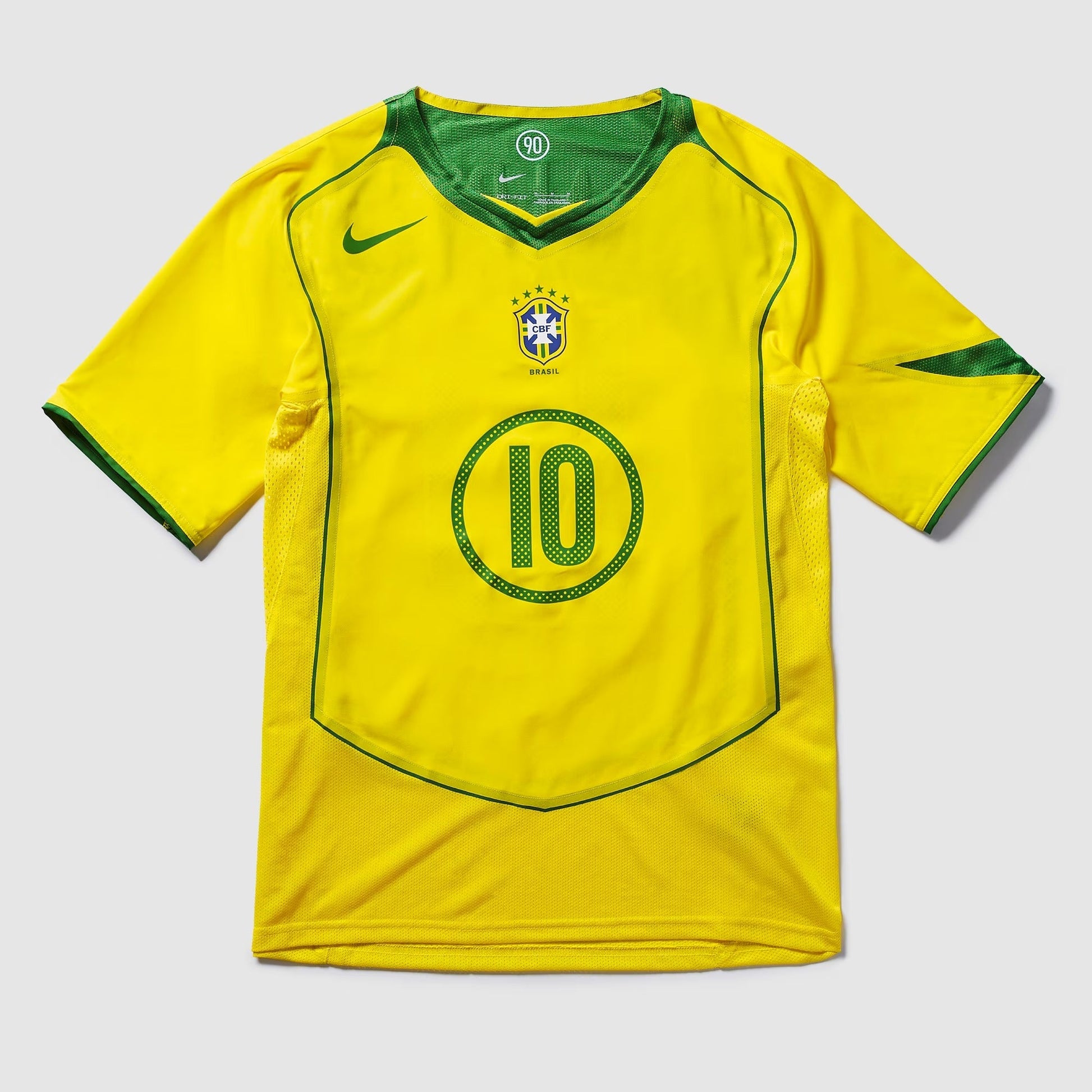 Camisa Nike Remake 2004 Seleção Brasileira Total 90 Ronaldinho, Camisas de Futebol, PIQUE DE JOGADOR, Reviva um dos períodos mais marcantes do futebol brasileiro com a Camisa Nike Remake 2004 Seleção Brasileira Total 90 Ronaldinho. Inspirada no icônico uniforme da linha Total 90 utilizado pela Seleção Brasileira em meados dos anos 2000, essa peça representa a era em que Ronaldinho encantava o mundo com sua habilidade, criatividade e alegria dentro de campo. O design segue o estilo característico da linha To