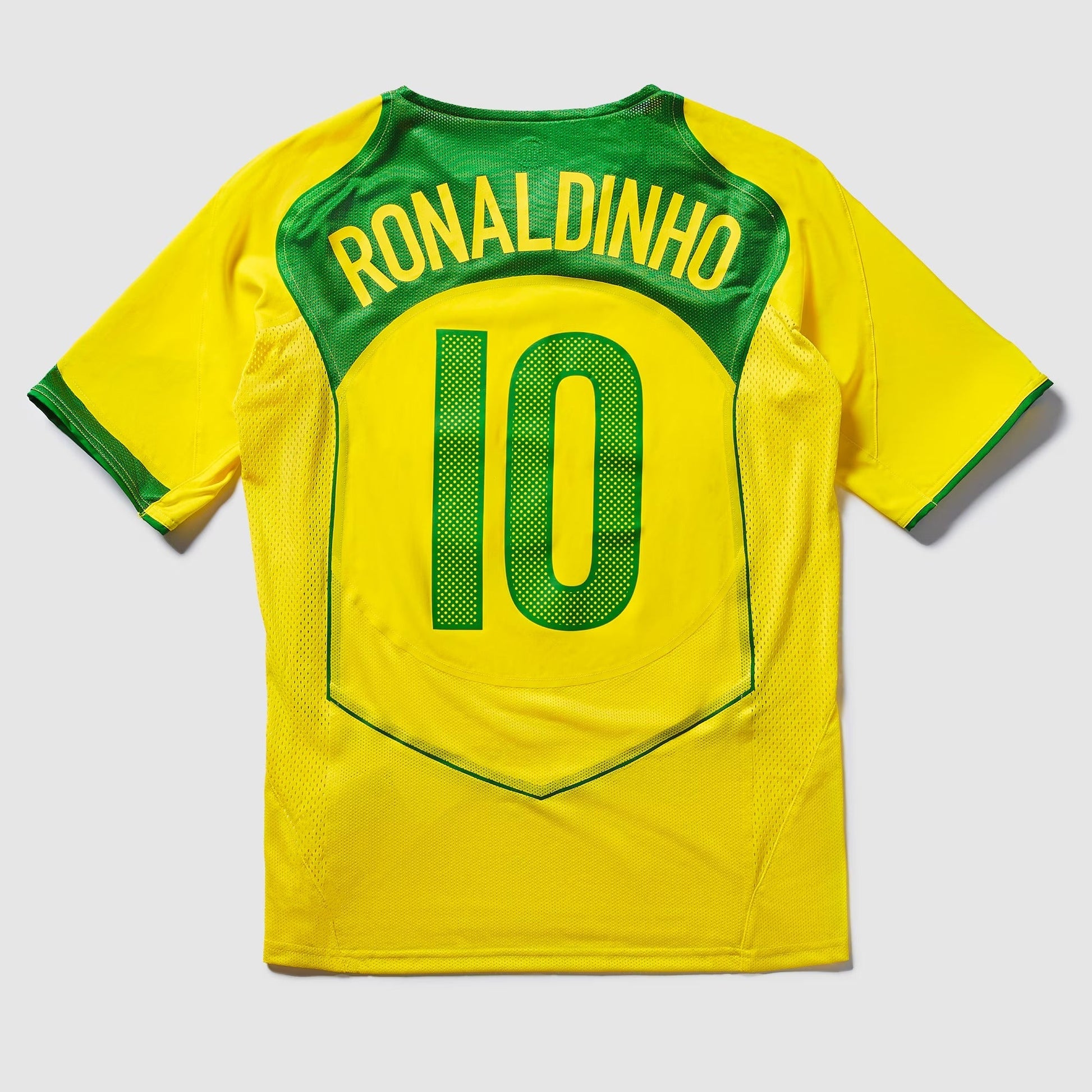 Camisa Nike Remake 2004 Seleção Brasileira Total 90 Ronaldinho, Camisas de Futebol, PIQUE DE JOGADOR, Reviva um dos períodos mais marcantes do futebol brasileiro com a Camisa Nike Remake 2004 Seleção Brasileira Total 90 Ronaldinho. Inspirada no icônico uniforme da linha Total 90 utilizado pela Seleção Brasileira em meados dos anos 2000, essa peça representa a era em que Ronaldinho encantava o mundo com sua habilidade, criatividade e alegria dentro de campo. O design segue o estilo característico da linha To