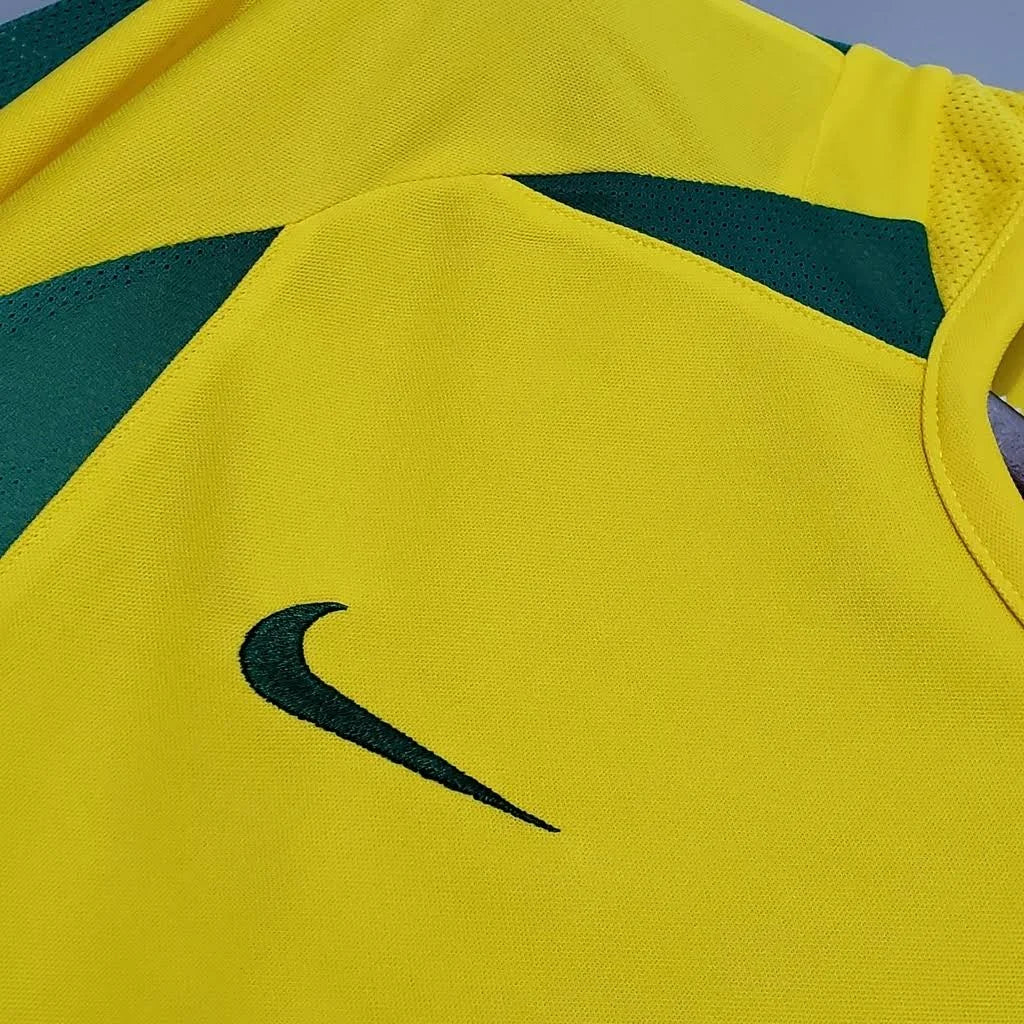 Camisa Nike Retrô Seleção Brasileira 2002 Home, , PIQUE DE JOGADOR, Reviva a emoção do pentacampeonato com a Camisa Nike Retrô Seleção Brasileira 2002 Home. Inspirada no uniforme titular utilizado pela Seleção Brasileira na histórica campanha da Copa do Mundo de 2002, essa camisa representa um dos momentos mais marcantes do futebol mundial. Com o clássico design amarelo com detalhes em verde, o modelo remete ao uniforme utilizado pela geração que entrou para a história ao conquistar o quinto título mundial 
