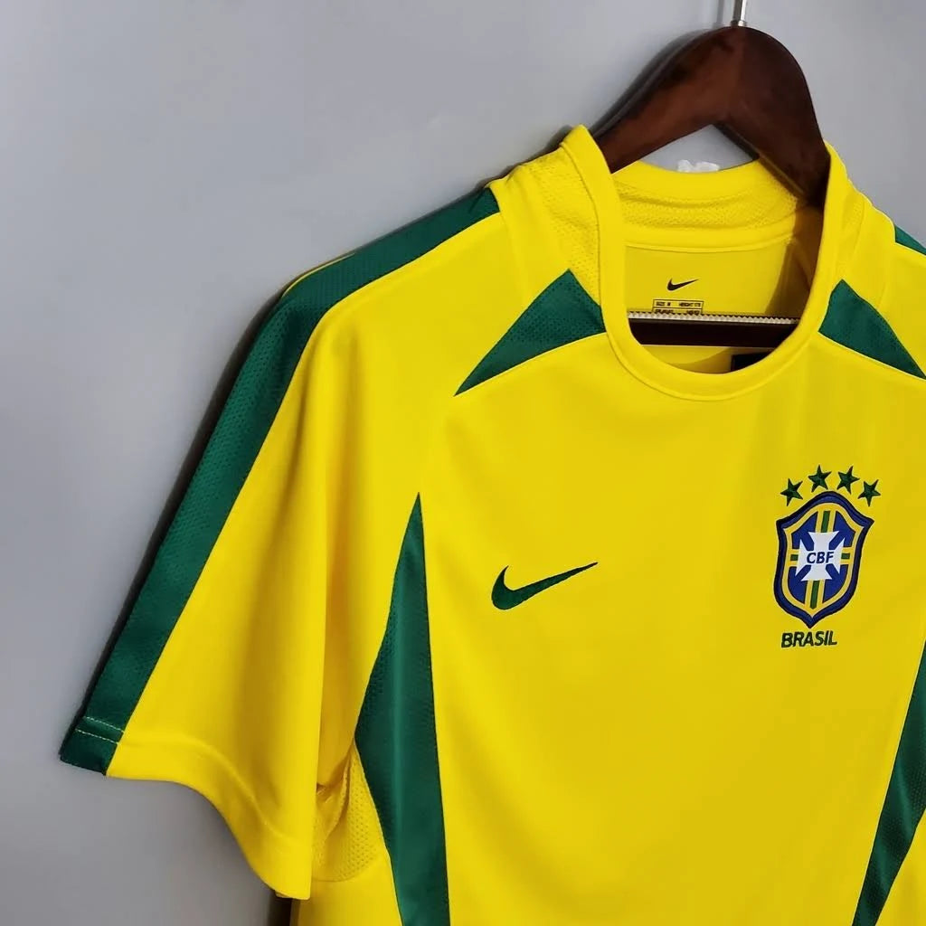 Camisa Nike Retrô Seleção Brasileira 2002 Home, , PIQUE DE JOGADOR, Reviva a emoção do pentacampeonato com a Camisa Nike Retrô Seleção Brasileira 2002 Home. Inspirada no uniforme titular utilizado pela Seleção Brasileira na histórica campanha da Copa do Mundo de 2002, essa camisa representa um dos momentos mais marcantes do futebol mundial. Com o clássico design amarelo com detalhes em verde, o modelo remete ao uniforme utilizado pela geração que entrou para a história ao conquistar o quinto título mundial 