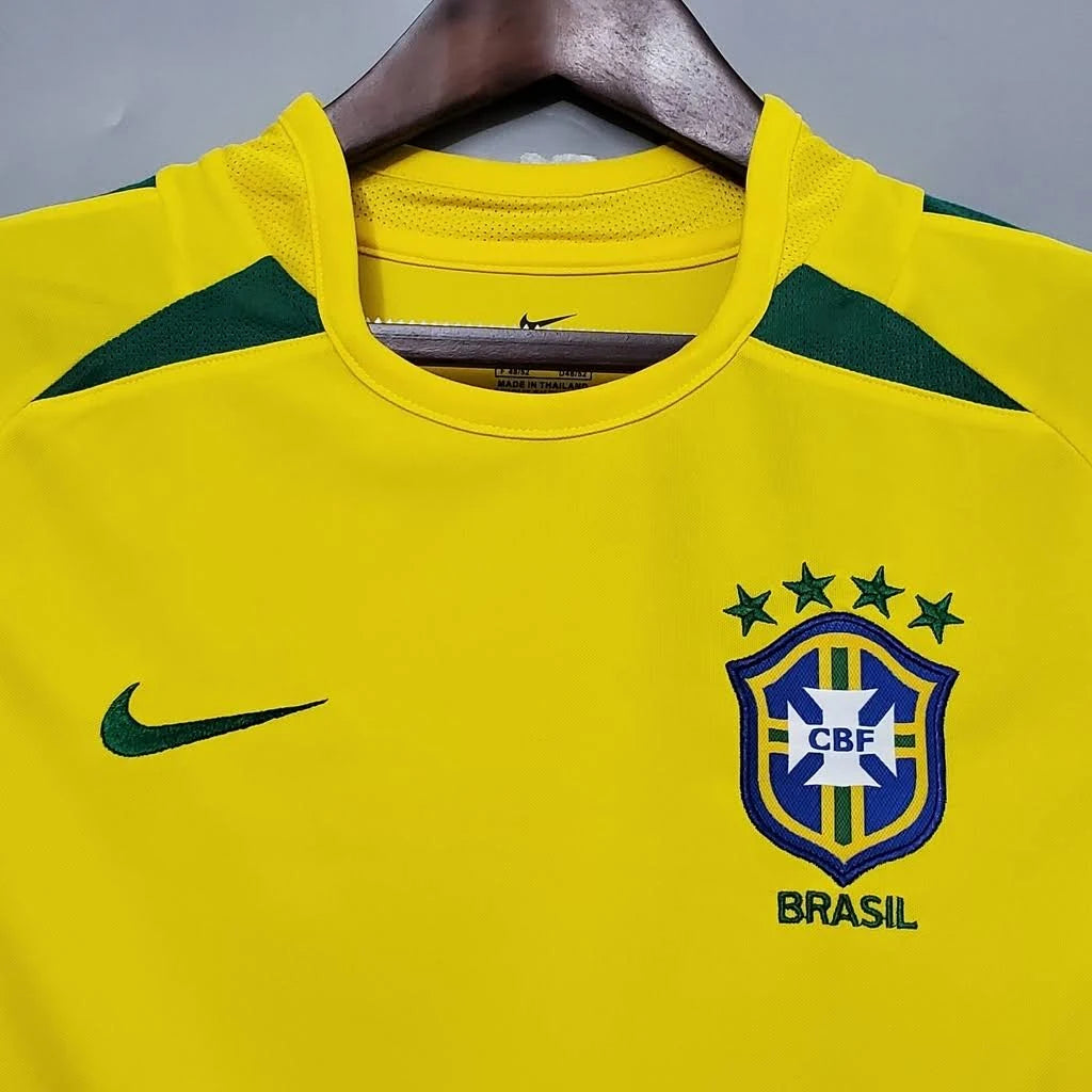 Camisa Nike Retrô Seleção Brasileira 2002 Home, , PIQUE DE JOGADOR, Reviva a emoção do pentacampeonato com a Camisa Nike Retrô Seleção Brasileira 2002 Home. Inspirada no uniforme titular utilizado pela Seleção Brasileira na histórica campanha da Copa do Mundo de 2002, essa camisa representa um dos momentos mais marcantes do futebol mundial. Com o clássico design amarelo com detalhes em verde, o modelo remete ao uniforme utilizado pela geração que entrou para a história ao conquistar o quinto título mundial 