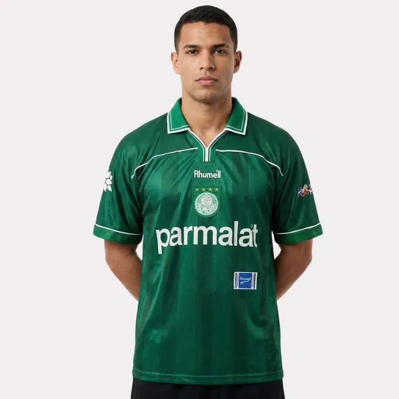 Camisa Retrô Palmeiras 1999 – Rhumell Comemorativa, Camisas de Futebol, PIQUE DE JOGADOR, A Camisa Retrô Palmeiras 1999 – Rhumell Comemorativa é uma homenagem fiel ao manto usado na maior conquista da história do Verdão: a Libertadores de 1999. Com patrocínio Parmalat, escudo bordado, gola clássica e etiqueta Rhumell original, essa peça revive uma das camisas mais icônicas do futebol brasileiro. Ideal para colecionadores e apaixonados pela história alviverde, o modelo reproduz com riqueza de detalhes o unif