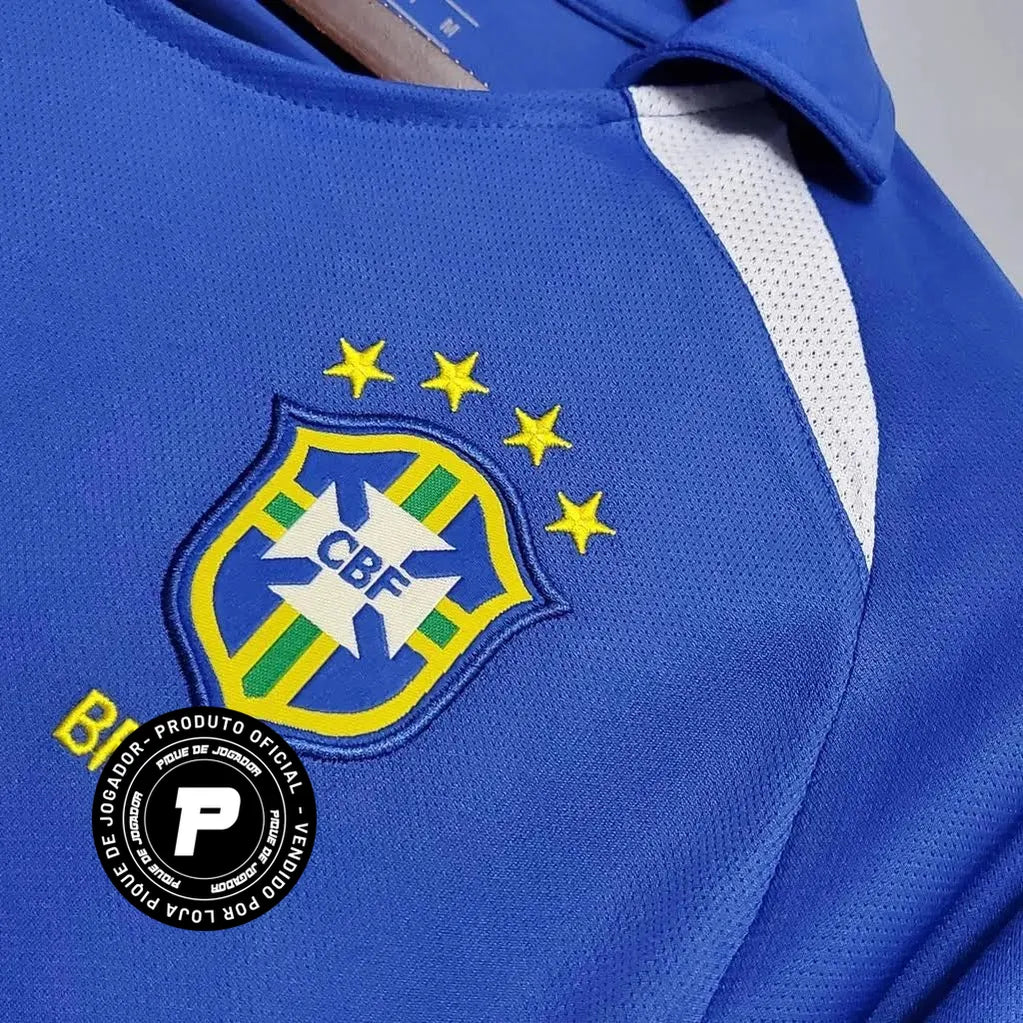 Camisa Retrô Seleção Brasilileira 2002 Away, Camisas de Futebol, PIQUE DE JOGADOR, Reviva um dos momentos mais gloriosos da história do futebol brasileiro com a Camisa Retrô Seleção Brasileira 2002 Away. Inspirada no uniforme reserva utilizado pela Seleção na campanha do pentacampeonato mundial, essa camisa representa a conquista histórica que consagrou o Brasil como a única seleção com cinco títulos da Copa do Mundo. O modelo em azul clássico ficou marcado nas partidas em que a Seleção precisou utilizar o 